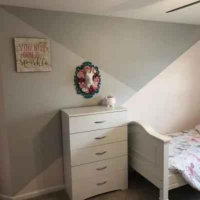 bedroom with a tri colored accent wall with dressed in front 