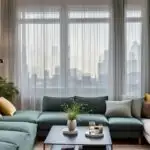 small living room with large window with sheer curtains and green couch and square coffee table (1)