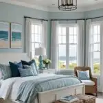 a coastal style bedroom with large windows, a bed and blue walls