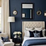 bedroom with bed, cream night stand, navy blue walls and large window with cream curtains