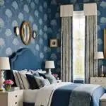 bedroom with bed, night stand, floor to ceiling window, and blue floral wallpaper