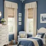 kids bedroom with bed, cream furniture, navy blue walls and large window with cream curtains