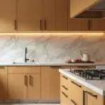 A kitchen with honey oak cabinets and marble countertops with veining of soft gray