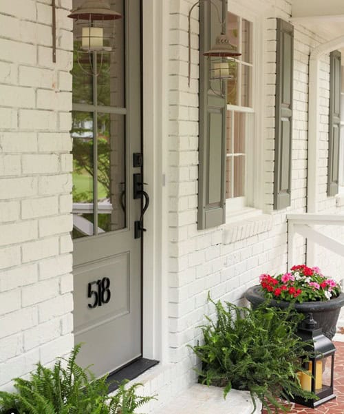 Exterior on a home painted white with green shutters and front door