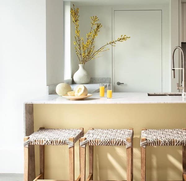 white painted walls in kitchen with yellow island and three stools