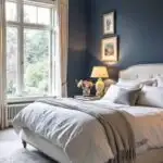 Bedroom with large window, bed and navy blue walls