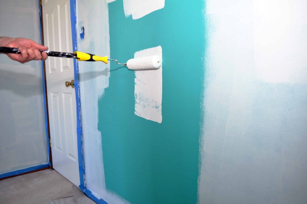 An image of a green wall being painted white