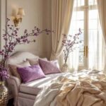 a neutral bedroom with a bed and large window and purple flowers