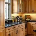 open kitchen with honey oak cabinets, black counters and black cabinet hardware