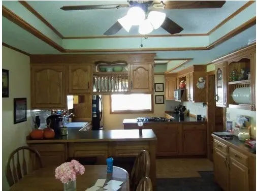 kitchen with orange wood , ceiling fan and light walls