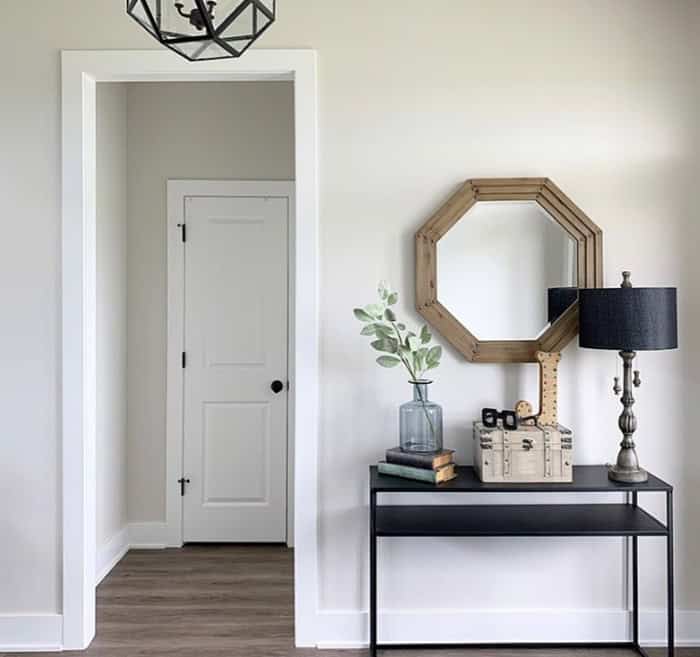 room with table and mirror above next to a doorway