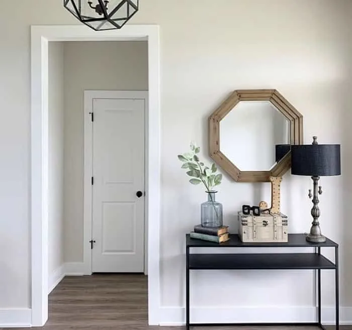room with table and mirror above next to a doorway